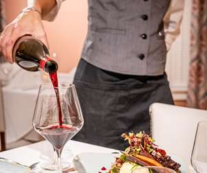 server pouring a glass of red wine